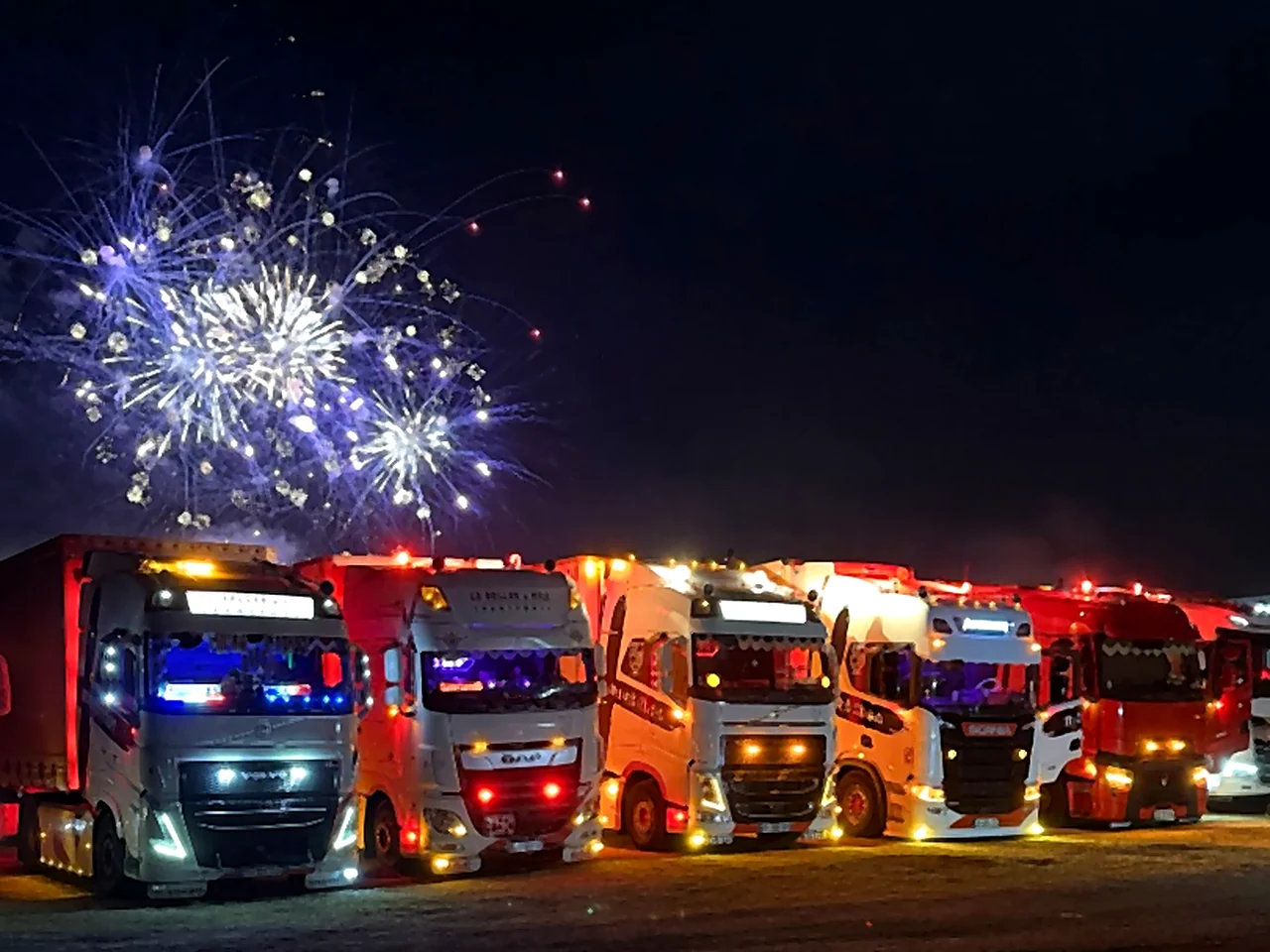 Convoi de camions Le Beller & Fils illuminés sous un feu d'artifice