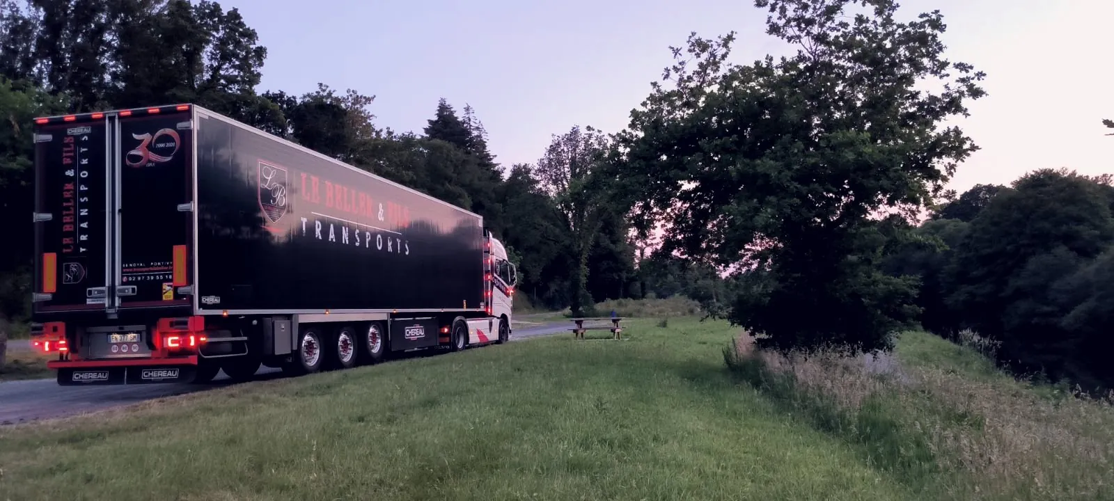 Arrière d'une semi-remorque Le Beller & Fils marquée 30 ans, au crépuscule
